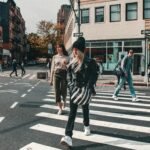 People crossing a busy street in a vibrant city setting during the day.