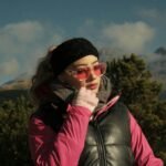 Stylish woman with pink sunglasses enjoying a sunny day in the mountains.